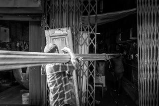 Mitarbeiter transportiert lange Lasten in einem Industrie- oder Lagerumfeld, symbolisch für den sicheren Umgang mit schweren Lasten